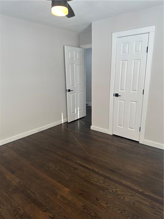 unfurnished room with dark hardwood / wood-style floors and ceiling fan