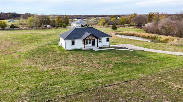 view of front of property featuring a front yard, covered porch, a water view, and a rural view