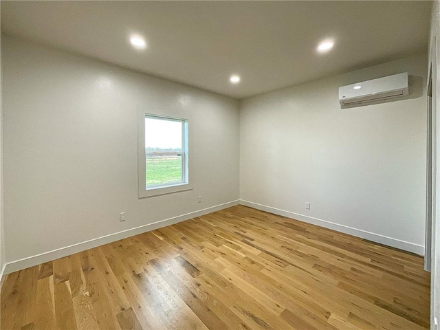 unfurnished room featuring light hardwood / wood-style floors and a wall mounted air conditioner