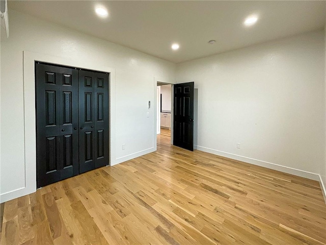 unfurnished bedroom with a closet and light hardwood / wood-style floors