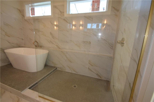 bathroom featuring tile patterned floors, a bathing tub, and tile walls