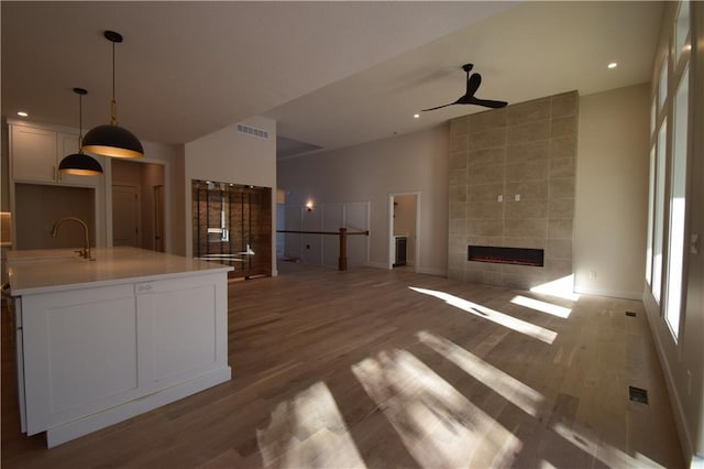 unfurnished living room with hardwood / wood-style flooring, ceiling fan, sink, and a fireplace