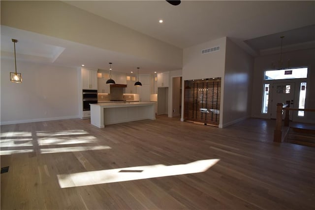 unfurnished living room featuring a towering ceiling and wood-type flooring