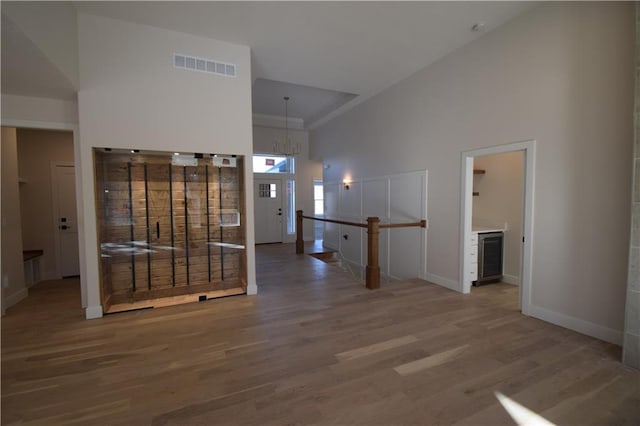 hall featuring a chandelier, hardwood / wood-style floors, and high vaulted ceiling