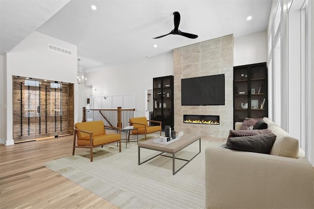 living area with visible vents, ceiling fan with notable chandelier, recessed lighting, light wood-style floors, and a fireplace