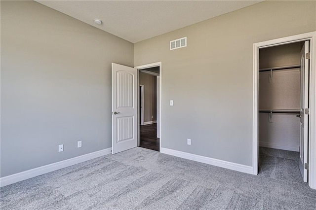 unfurnished bedroom featuring a closet, a spacious closet, and carpet