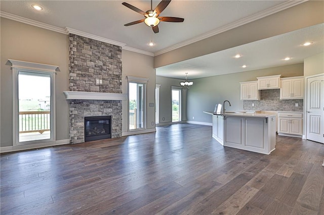 kitchen featuring a fireplace, crown molding, dark hardwood / wood-style floors, white cabinets, and a kitchen island with sink