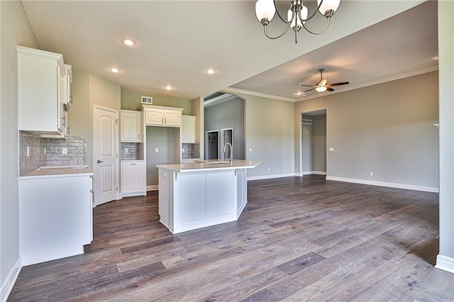 kitchen with ornamental molding, decorative backsplash, a center island with sink, and dark hardwood / wood-style floors