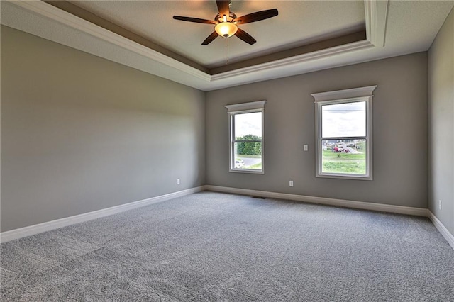 carpeted empty room with a tray ceiling and ceiling fan