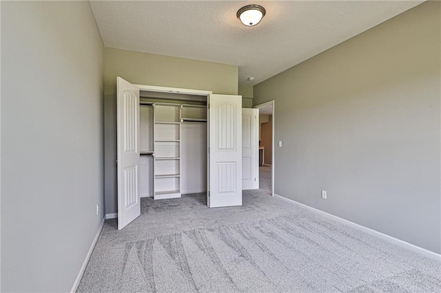 unfurnished bedroom with light colored carpet, a textured ceiling, and a closet