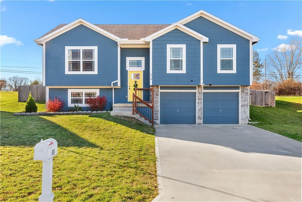 raised ranch with a garage and a front lawn