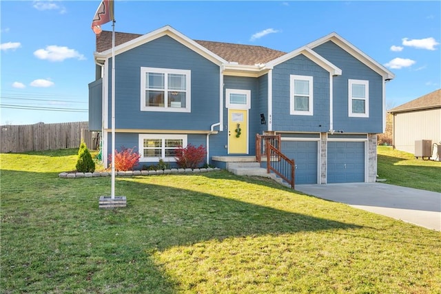 raised ranch with central AC unit, a garage, and a front yard