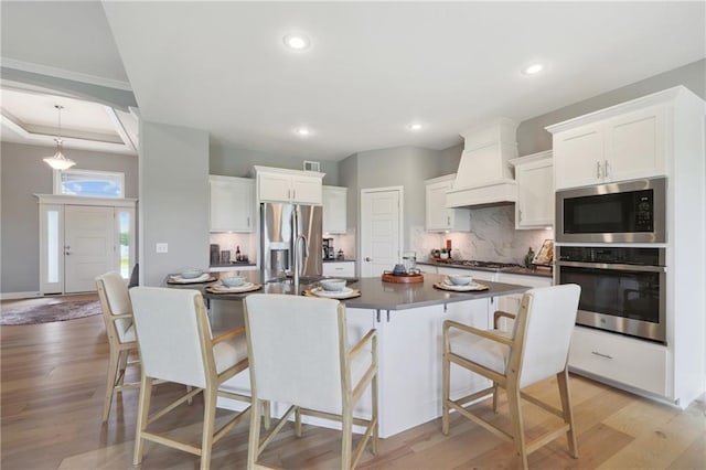 kitchen featuring white cabinetry, light wood-type flooring, appliances with stainless steel finishes, and custom range hood