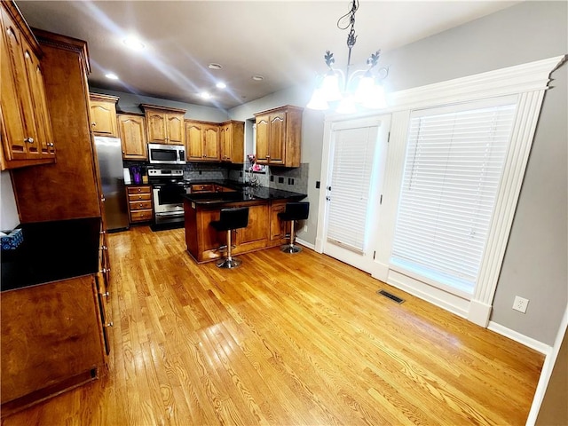 kitchen featuring a kitchen breakfast bar, light hardwood / wood-style flooring, a kitchen island, stainless steel appliances, and a chandelier