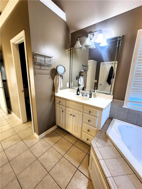 bathroom with vanity, tile patterned flooring, ornamental molding, a textured ceiling, and tiled bath