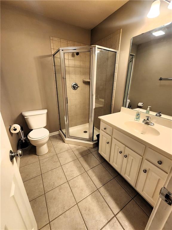 bathroom with tile patterned floors, vanity, toilet, and a shower with shower door