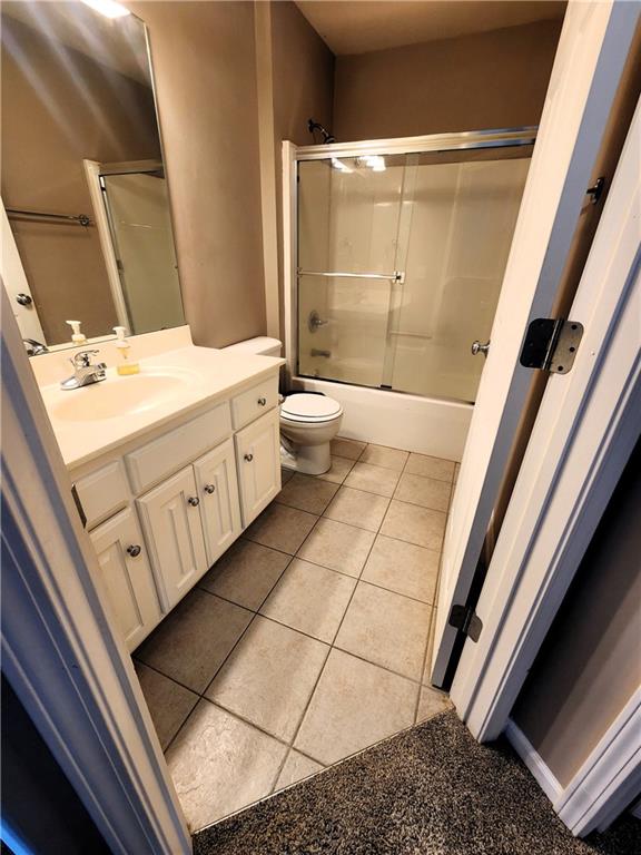 full bathroom featuring tile patterned flooring, vanity, toilet, and bath / shower combo with glass door