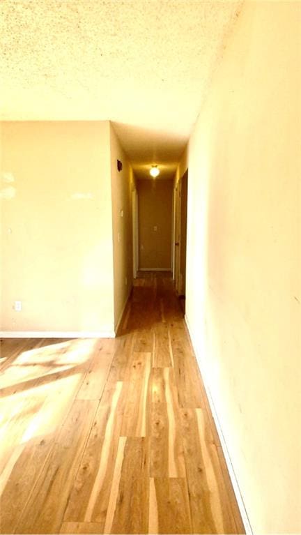 hallway featuring wood-type flooring and a textured ceiling