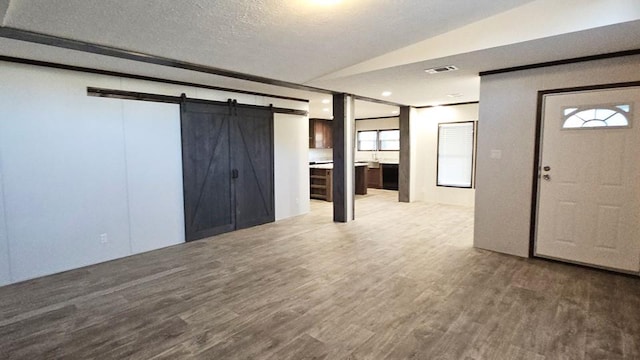 entryway with a healthy amount of sunlight, a barn door, lofted ceiling, and wood-type flooring