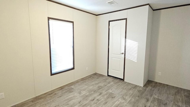 spare room featuring crown molding and light hardwood / wood-style floors