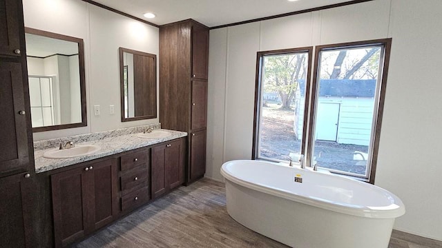 bathroom with hardwood / wood-style floors, vanity, a bathtub, and ornamental molding