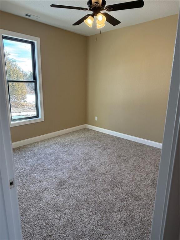 empty room featuring ceiling fan, carpet flooring, visible vents, and baseboards