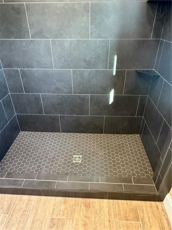 bathroom featuring tiled shower and wood finished floors