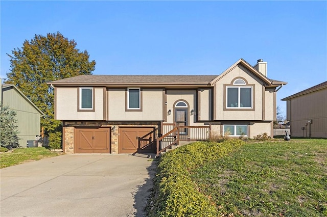 split foyer home featuring central AC unit, a garage, and a front yard