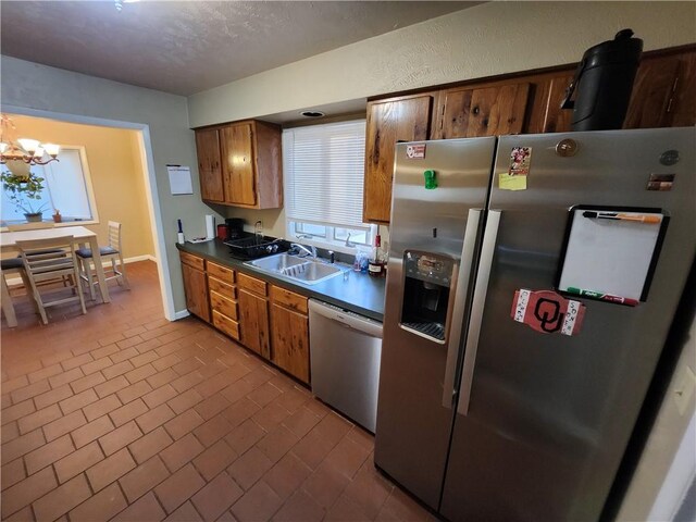 2716 N 10th St, Independence, KS 67301 - kitchen with appliances with stainless steel finishes, a sink, a chandelier, brick patterned flooring, and baseboards
