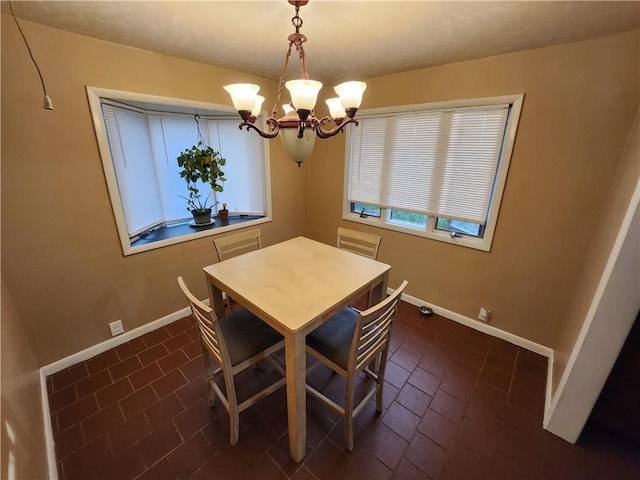 dining room with dark tile patterned flooring and a chandelier