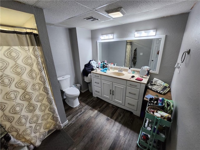 bathroom with a paneled ceiling, a shower with curtain, hardwood / wood-style floors, vanity, and toilet