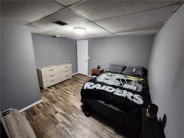 bedroom featuring a paneled ceiling and dark wood-type flooring