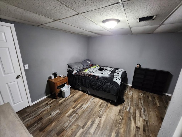 bedroom with dark wood-type flooring and a paneled ceiling