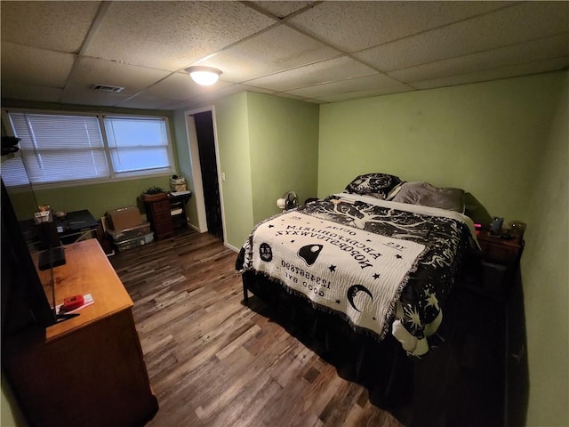 bedroom featuring a drop ceiling and hardwood / wood-style floors