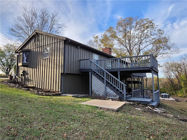 rear view of property featuring a lawn and a deck