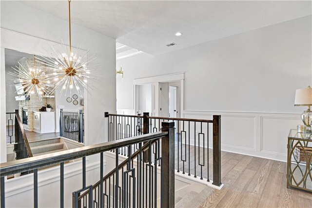 24912 W 98th Pl, Lenexa, KS 66227 - corridor with an upstairs landing, light wood-style floors, a chandelier, a decorative wall, and a wainscoted wall