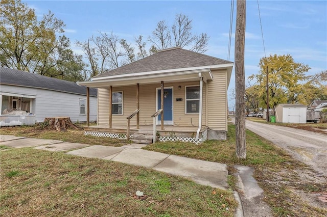 bungalow-style home with a porch and a storage shed