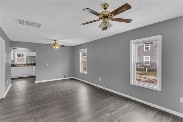 unfurnished living room featuring dark hardwood / wood-style floors, ceiling fan, sink, and a textured ceiling