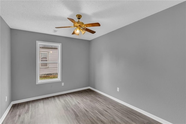 empty room with ceiling fan, a textured ceiling, and hardwood / wood-style flooring