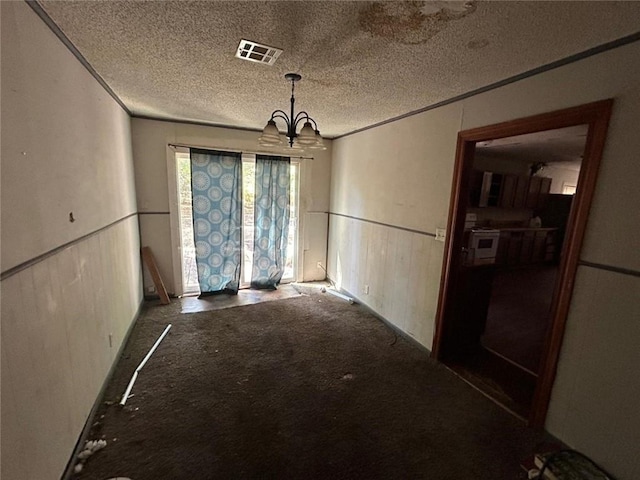 unfurnished dining area with an inviting chandelier, carpet, and a textured ceiling