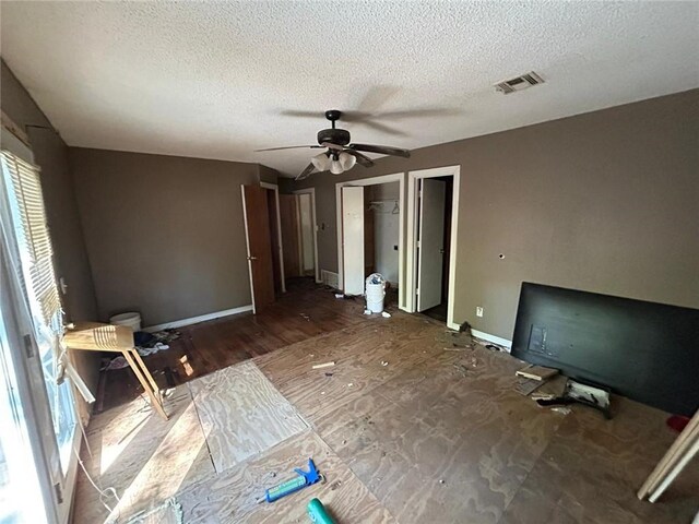 interior space featuring a walk in closet, a textured ceiling, ceiling fan, and dark hardwood / wood-style floors