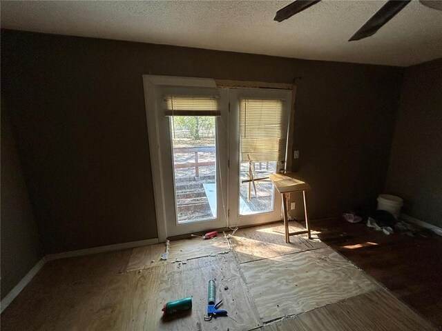 doorway to outside with wood-type flooring, a textured ceiling, and ceiling fan