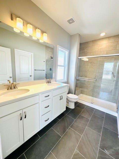 bathroom with vanity, toilet, and a shower with door