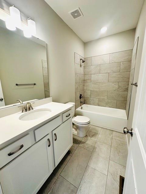 full bathroom featuring vanity, tiled shower / bath combo, and toilet