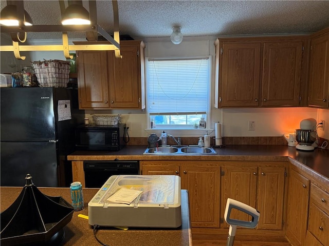 kitchen with a textured ceiling, black appliances, and sink