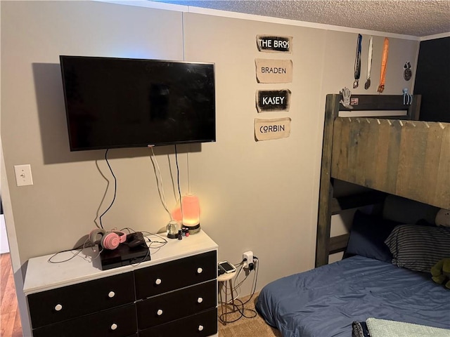 bedroom featuring a textured ceiling, ornamental molding, and light hardwood / wood-style flooring