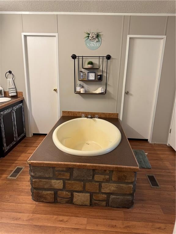 bathroom featuring hardwood / wood-style floors, a textured ceiling, and a washtub