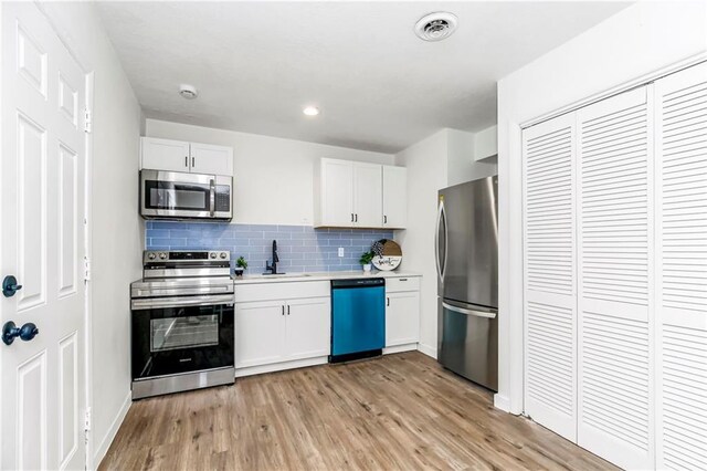 kitchen with white cabinets, stainless steel appliances, and light hardwood / wood-style flooring