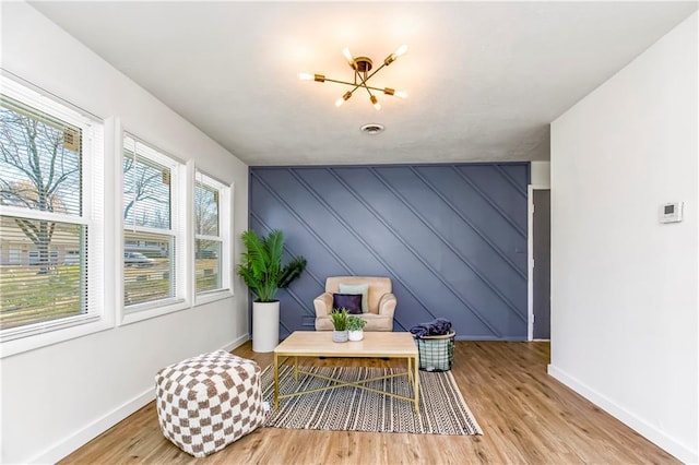 sitting room featuring a healthy amount of sunlight, an inviting chandelier, and light hardwood / wood-style flooring