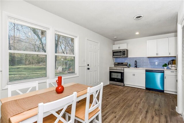 kitchen with white cabinets, a healthy amount of sunlight, dark hardwood / wood-style flooring, and stainless steel appliances